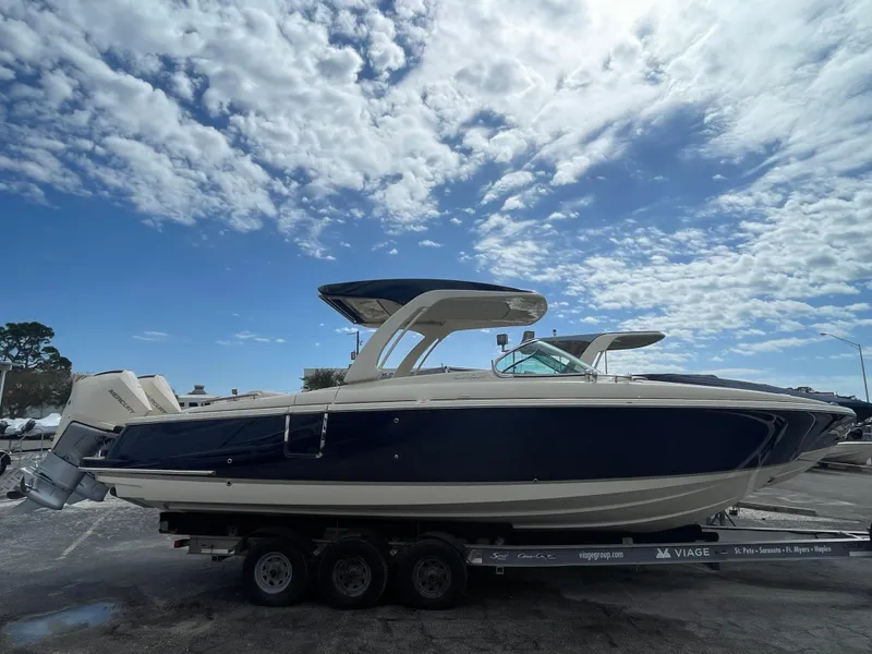 Slide: The Image of 2024 Chris-Craft Launch 31 GT boat on a trailer under a partly cloudy sky. - 0