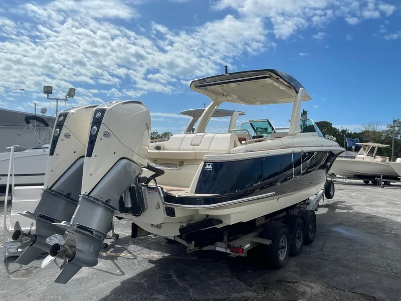 Slide: The Image of 2024 Chris-Craft Launch 31 GT boat on trailer, dual outboard engines, sunny day. - 2