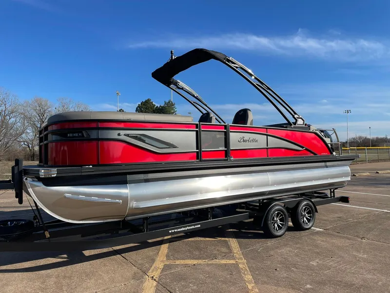 Slide: The Image of 2024 Barletta CORSA 23UCA pontoon boat with red and black exterior on a trailer. - 3