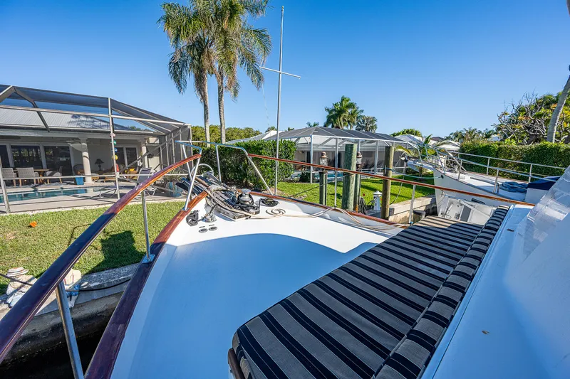 Slide: The Image of 1983 Krogen 42 yacht deck with striped seating, docked near palm trees and houses. - 14