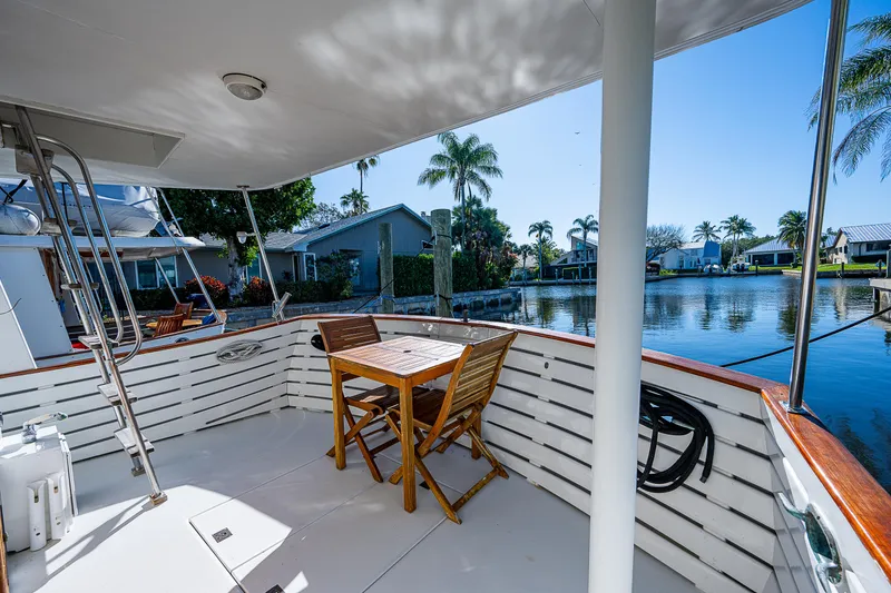 Slide: The Image of 1983 Krogen 42 yacht deck with table, chairs, and waterfront view. - 2
