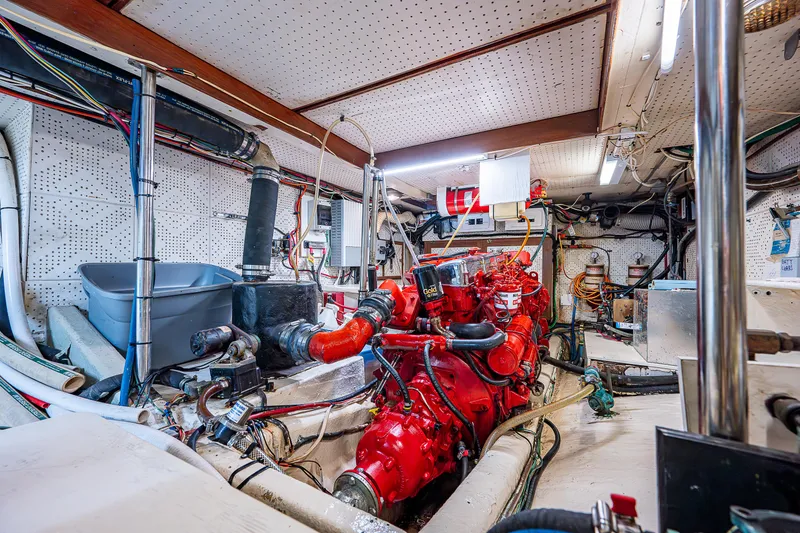 Slide: The Image of Engine room of a 1983 Krogen 42 boat, featuring a red engine and various equipment. - 21
