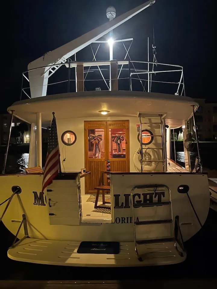 Slide: The Image of 1983 Krogen 42 yacht docked at night, illuminated with warm lights, featuring a U.S. flag. - 24
