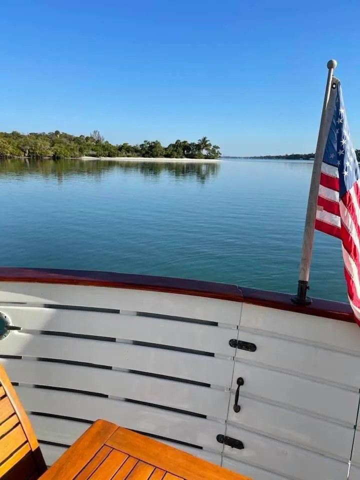 Slide: The Image of 1983 Krogen 42 boat with American flag, calm water, and distant shoreline. - 26