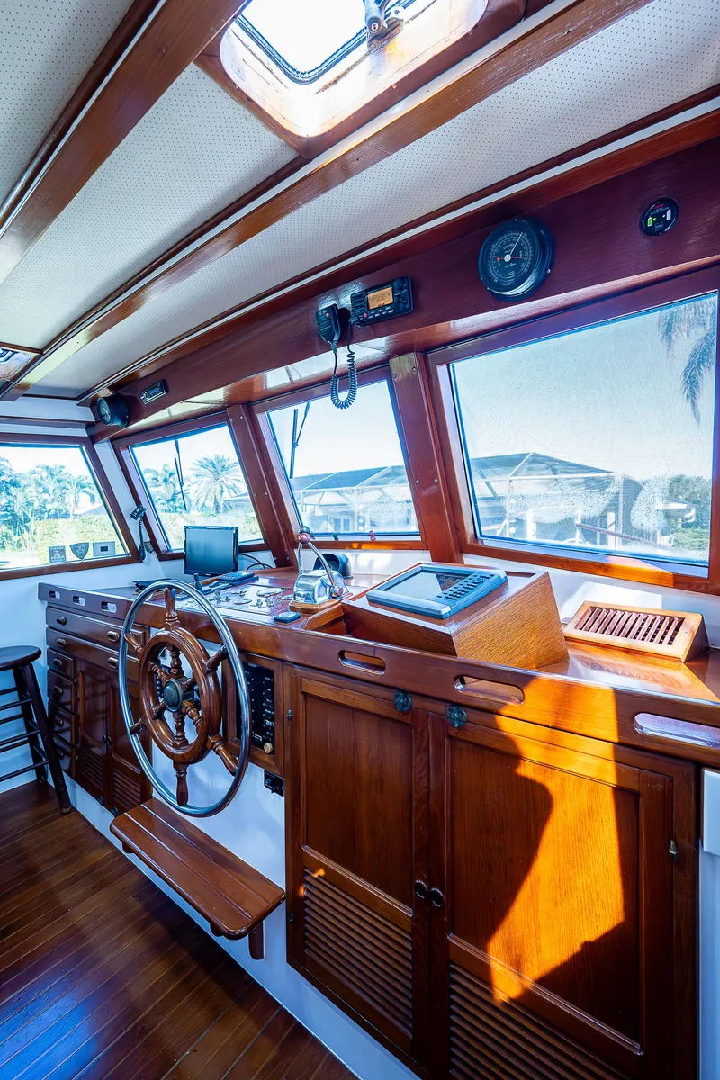 Slide: The Image of 1983 Krogen 42 yacht interior with wooden helm, navigation equipment, and large windows. - 34
