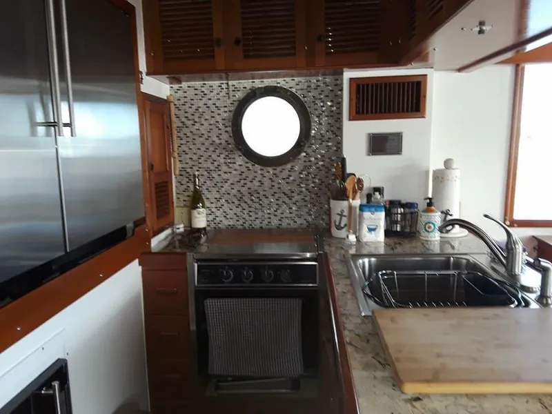 Slide: The Image of 1983 Krogen 42 yacht kitchen with porthole, stainless steel appliances, and granite countertops. - 6