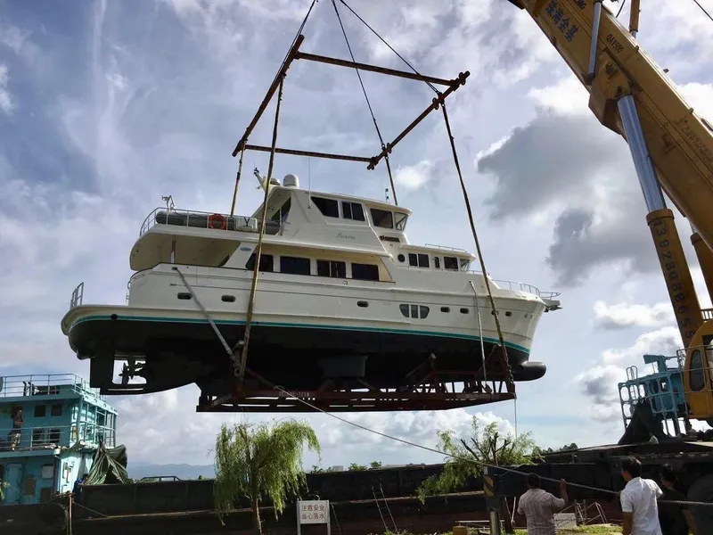 Slide: The Image of Selene 72 Classic Explorer yacht being lifted by crane, 2026 model, under a cloudy sky. - 7