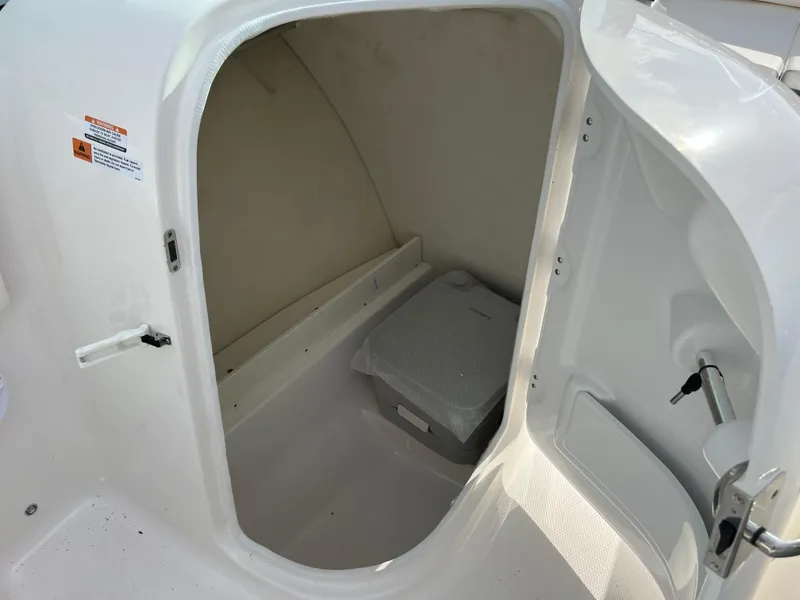 Slide: The Image of 2024 Robalo R207 Dual Console boat storage compartment with portable toilet. - 11