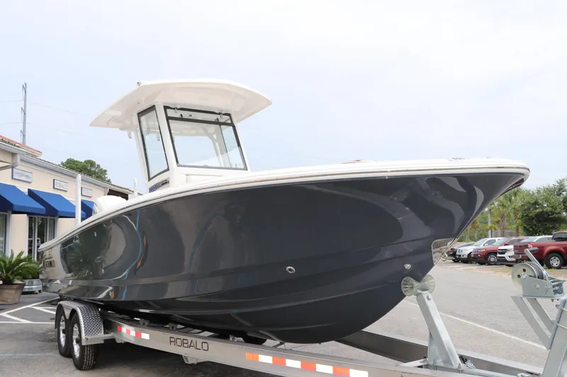 Slide: The Image of 2024 Robalo 266 Cayman boat on trailer, sleek design, parked outdoors. - 2