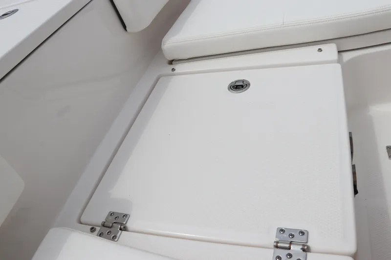 Slide: The Image of 2024 Robalo 266 Cayman boat storage compartment with white cushioned seating. - 26