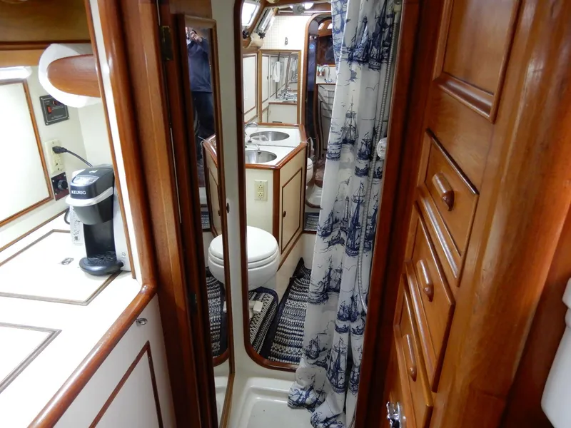 Slide: The Image of 1985 Barnett Offshore yacht interior with wooden cabinetry, compact kitchen, and nautical-themed bathroom. - 11