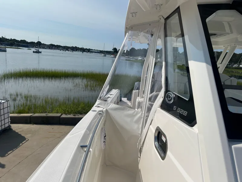 Slide: The Image of 2024 Pursuit S 328 Sport boat docked by a serene waterfront. - 13