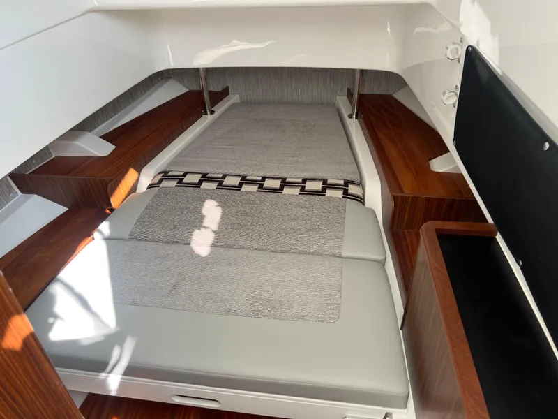 Slide: The Image of 2024 Pursuit S 328 Sport cabin interior with sleek wood accents and comfortable bedding. - 27