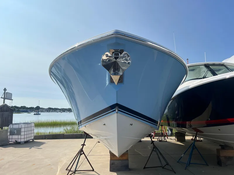 Slide: The Image of 2024 Pursuit S 328 Sport boat on stands by the water, front view. - 4
