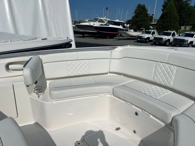Slide: The Image of 2024 Pursuit S 328 Sport boat with white cushioned seating in a marina setting. - 8