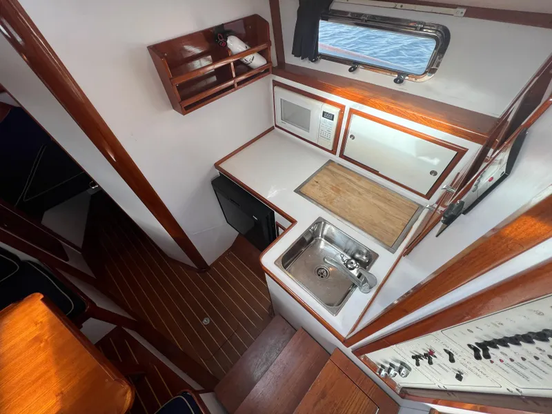 Slide: The Image of Compact galley of 2000 Bruckmann Bluestar 29.9 boat with sink, microwave, and wooden cabinetry. - 22