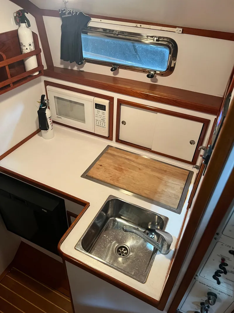 Slide: The Image of Compact galley kitchen in 2000 Bruckmann Bluestar 29.9 boat with sink, microwave, and cutting board. - 29