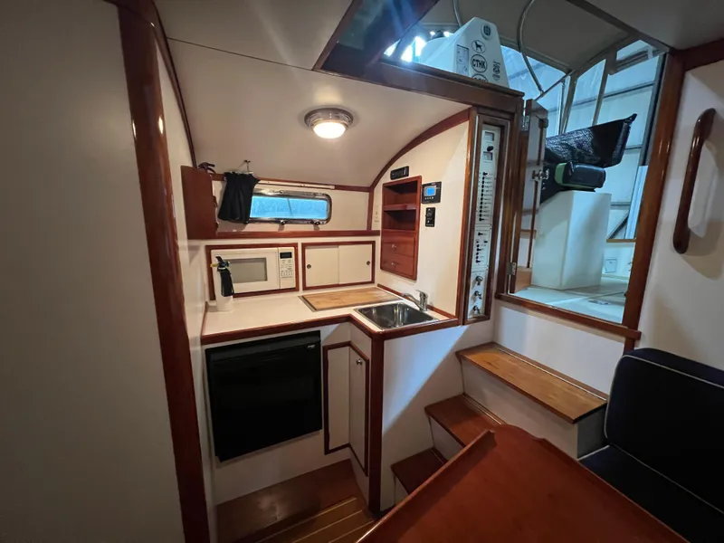 Slide: The Image of Compact kitchen area in a 2000 Bruckmann Bluestar 29.9 boat with wooden cabinetry and modern appliances. - 31