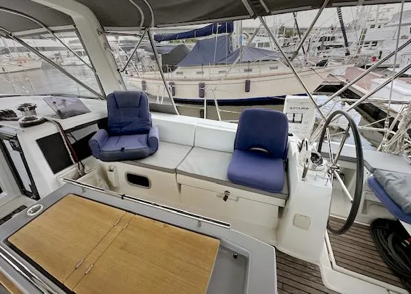 Slide: The Image of 2019 Beneteau Oceanis 48 yacht cockpit with seating, table, and steering wheel in marina. - 13