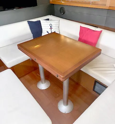 Slide: The Image of Interior of 2019 Beneteau Oceanis 48 with wooden table and cushioned seating. - 22