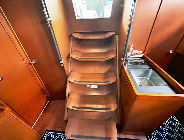 Slide: The Image of Interior of 2019 Beneteau Oceanis 48 yacht with wooden stairs and compact sink area. - 25