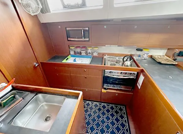Slide: The Image of Interior of 2019 Beneteau Oceanis 48 yacht kitchen with sink, stove, and microwave. - 26