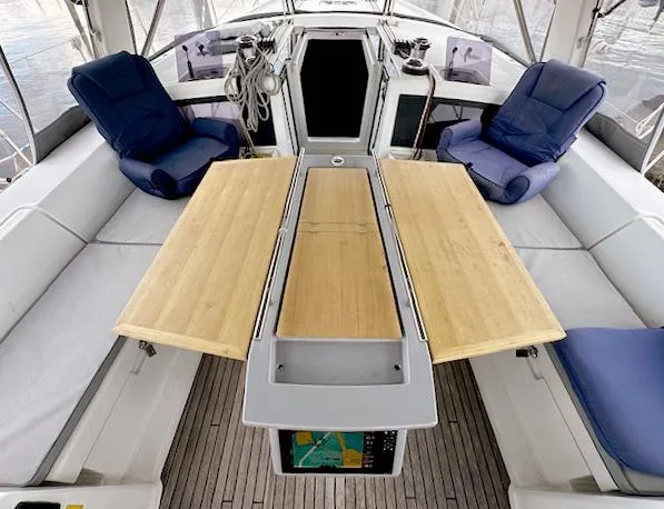 Slide: The Image of 2019 Beneteau Oceanis 48 cockpit with wooden table, cushioned seating, and navigation equipment. - 6