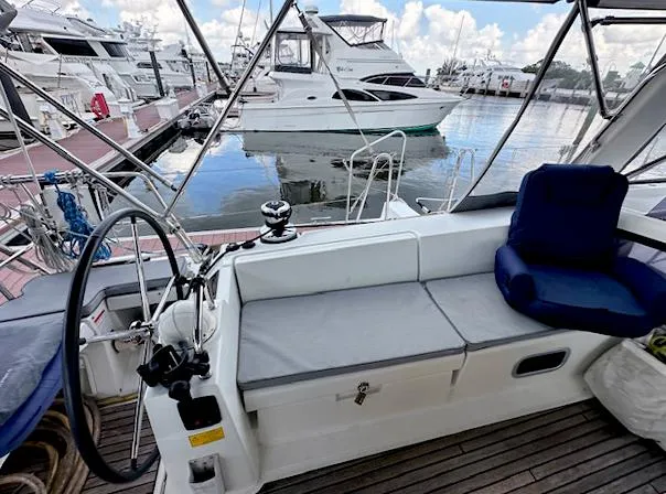 Slide: The Image of 2019 Beneteau Oceanis 48 yacht cockpit with marina view, featuring comfortable seating and steering wheel. - 9