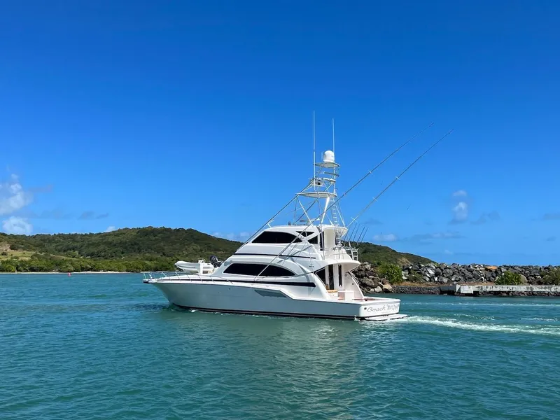 Slide: The Image of 2004 Bertram 670 yacht cruising in clear blue waters near a green island. - 14