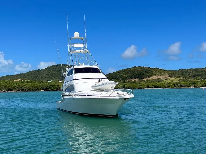 Slide: The Image of 2004 Bertram 670 yacht on clear blue water with scenic island backdrop. - 17