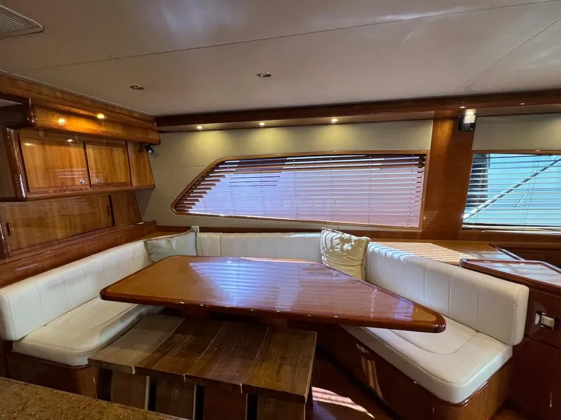 Slide: The Image of Luxurious interior of a 2004 Bertram 670 yacht with wooden dining table and white seating. - 29