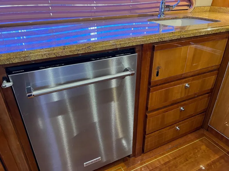 Slide: The Image of 2004 Bertram 670 yacht kitchen with stainless steel dishwasher and wooden cabinetry. - 31