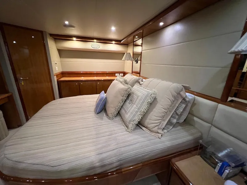 Slide: The Image of Luxurious bedroom interior of a 2004 Bertram 670 yacht with plush bedding and wooden accents. - 39