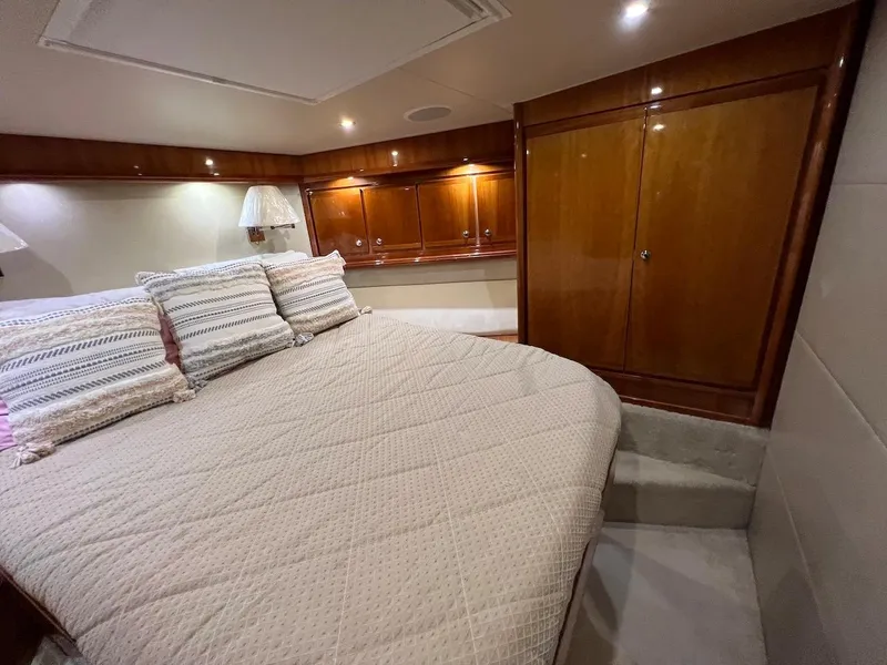 Slide: The Image of Luxurious bedroom interior of a 2004 Bertram 670 yacht with wooden cabinets and cozy bedding. - 42