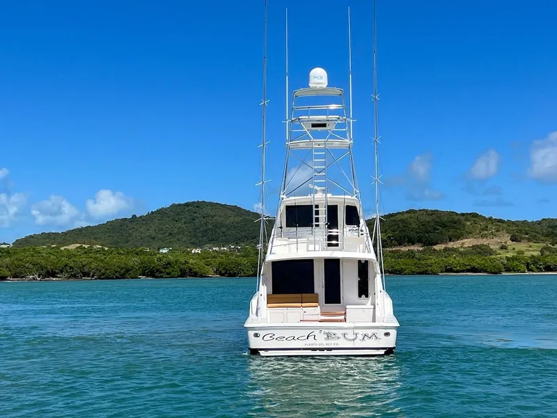 Slide: The Image of 2004 Bertram 670 yacht Beach Bum on calm waters with scenic island backdrop. - 7