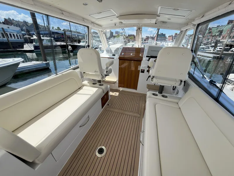 Slide: The Image of 2024 MJM 35 boat interior with white seating and wooden flooring at a marina. - 11