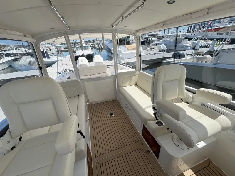 Slide: The Image of 2024 MJM 35 boat interior with white seating and wood flooring at a marina. - 13