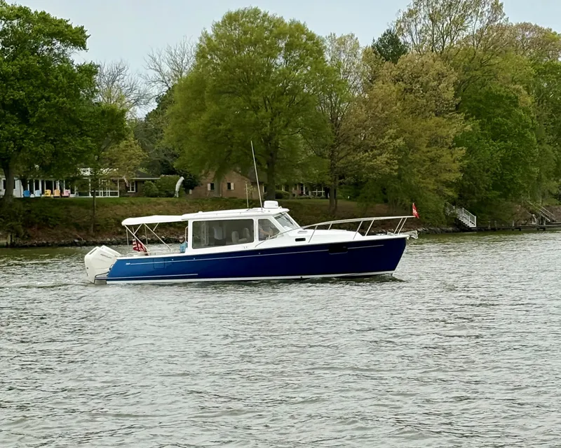 Slide: The Image of 2024 MJM 35 boat cruising on a calm river with lush green trees in the background. - 23