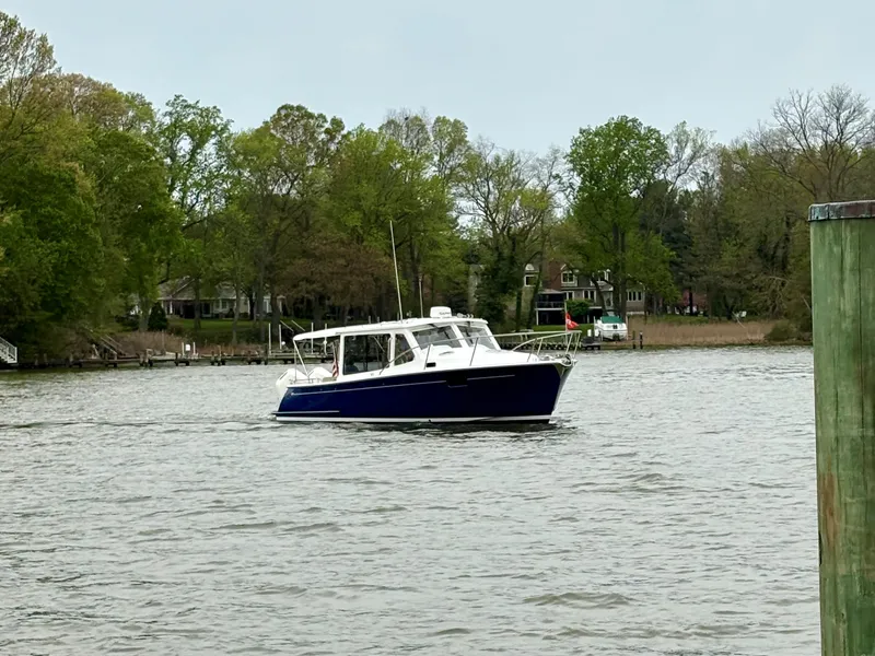Slide: The Image of 2024 MJM 35 boat cruising on a calm river with lush green trees in the background. - 24