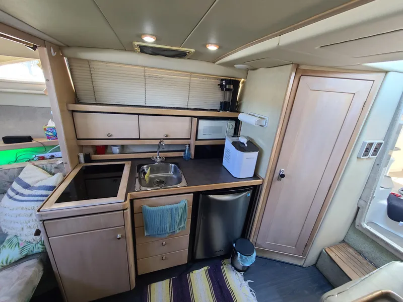 Slide: The Image of 1995 Bayliner Avanti boat kitchen with sink, fridge, and storage cabinets. - 13