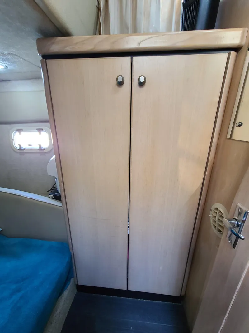 Slide: The Image of 1995 Bayliner Avanti cabin interior with wooden storage cabinet and blue bedding. - 16