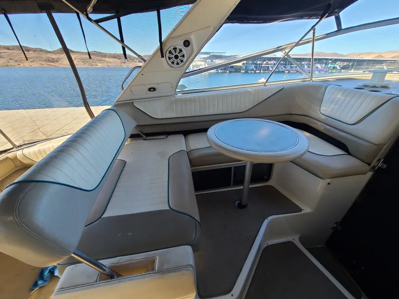 Slide: The Image of 1995 Bayliner Avanti boat interior with seating and table, docked by a lake. - 7