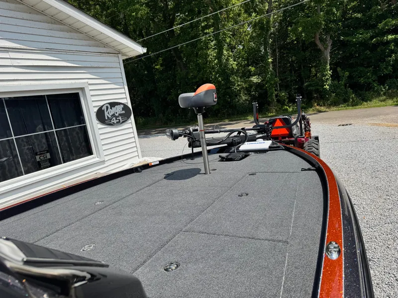 Slide: The Image of 2024 Ranger Z521R CUP boat deck near a white building, surrounded by trees. - 6
