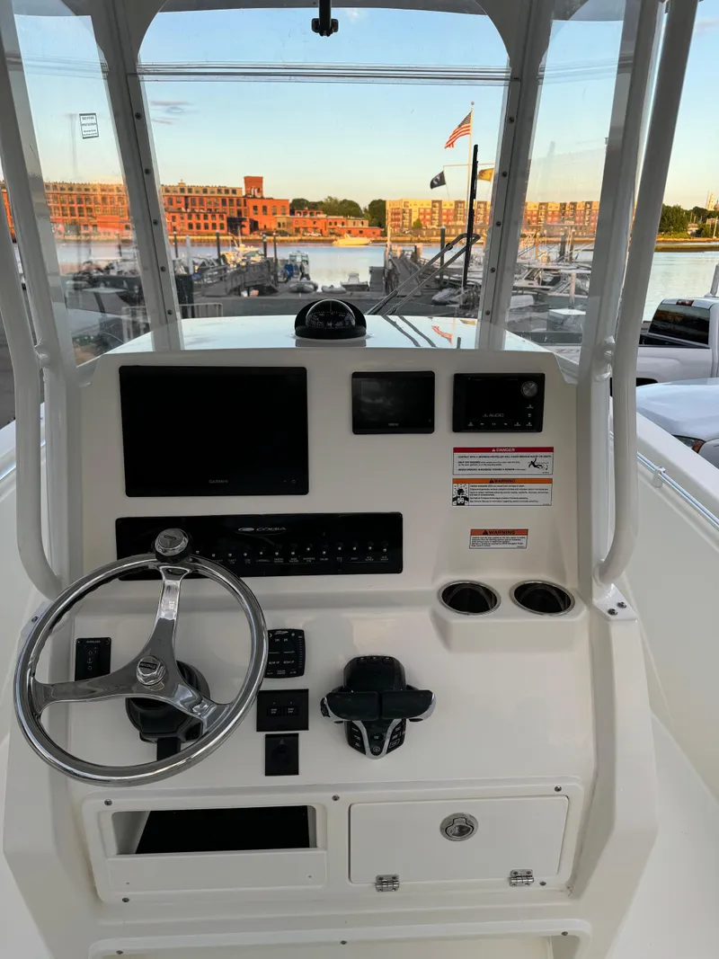 Slide: The Image of 2024 Cobia 240 Center Console boat helm with steering wheel and control panel. - 21