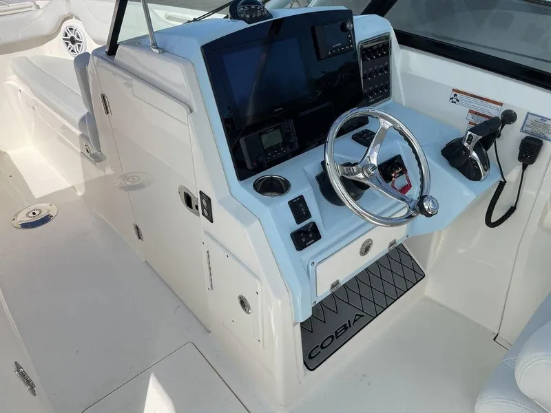 Slide: The Image of 2022 Cobia 280 DC boat helm with steering wheel and navigation controls. - 7