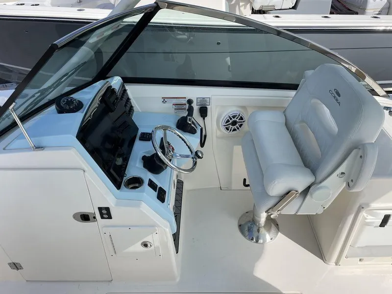 Slide: The Image of 2022 Cobia 280 DC boat helm with white captain's chair and modern controls. - 9
