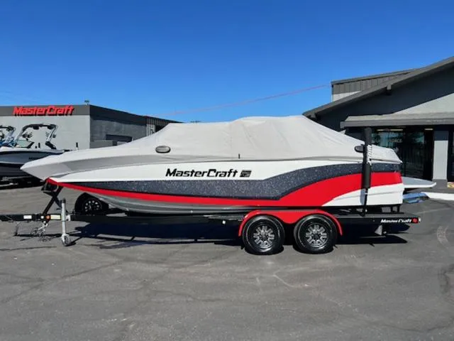 Slide: The Image of 2018 MasterCraft XT22 boat with cover on trailer in dealership lot. - 22