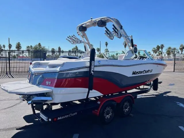 Slide: The Image of 2018 MasterCraft XT22 boat on trailer, red and white, parked outdoors. - 6