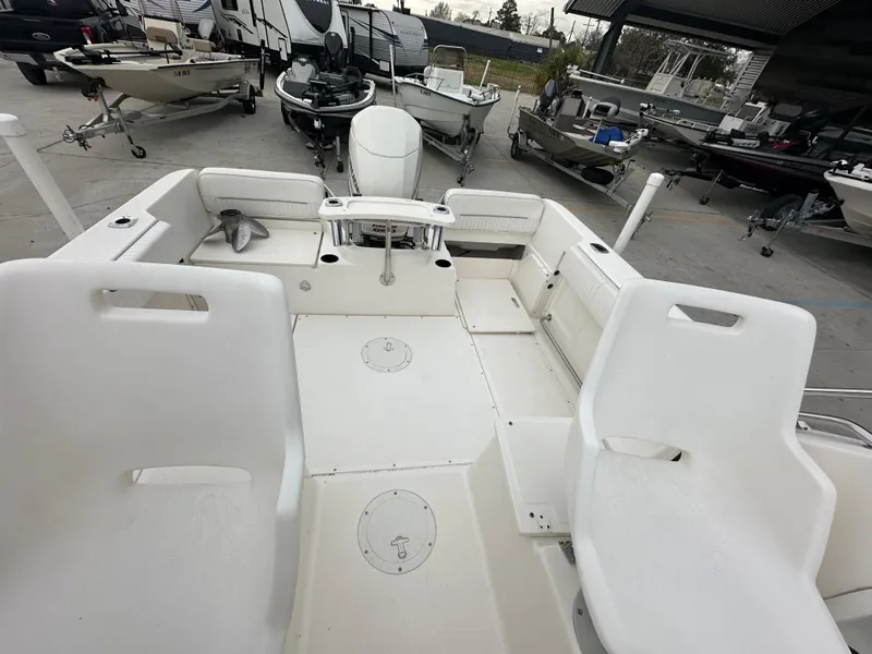 Slide: The Image of 1998 Boston Whaler 23 Conquest boat interior with white seating and deck, docked among other boats. - 11