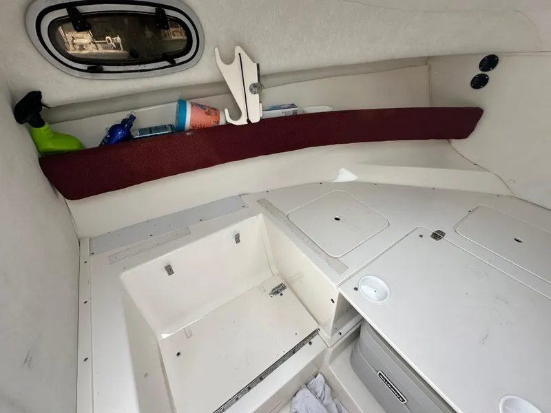 Slide: The Image of 1998 Boston Whaler 23 Conquest cabin interior with storage compartments and porthole. - 30